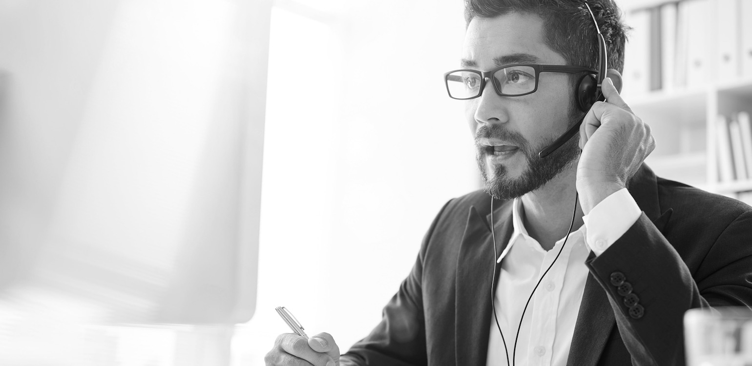 Support employee with headset in front of computer